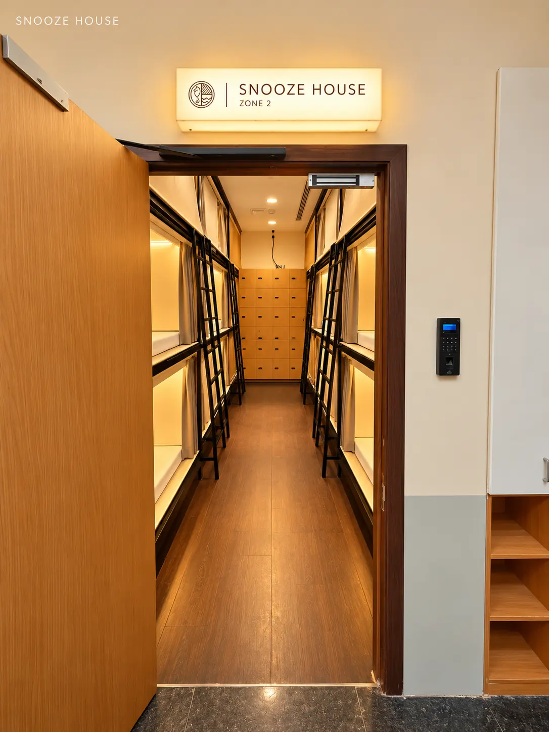 Zone 2 door open onto a corridor of warm-lit pods, with a biometric reader beside it